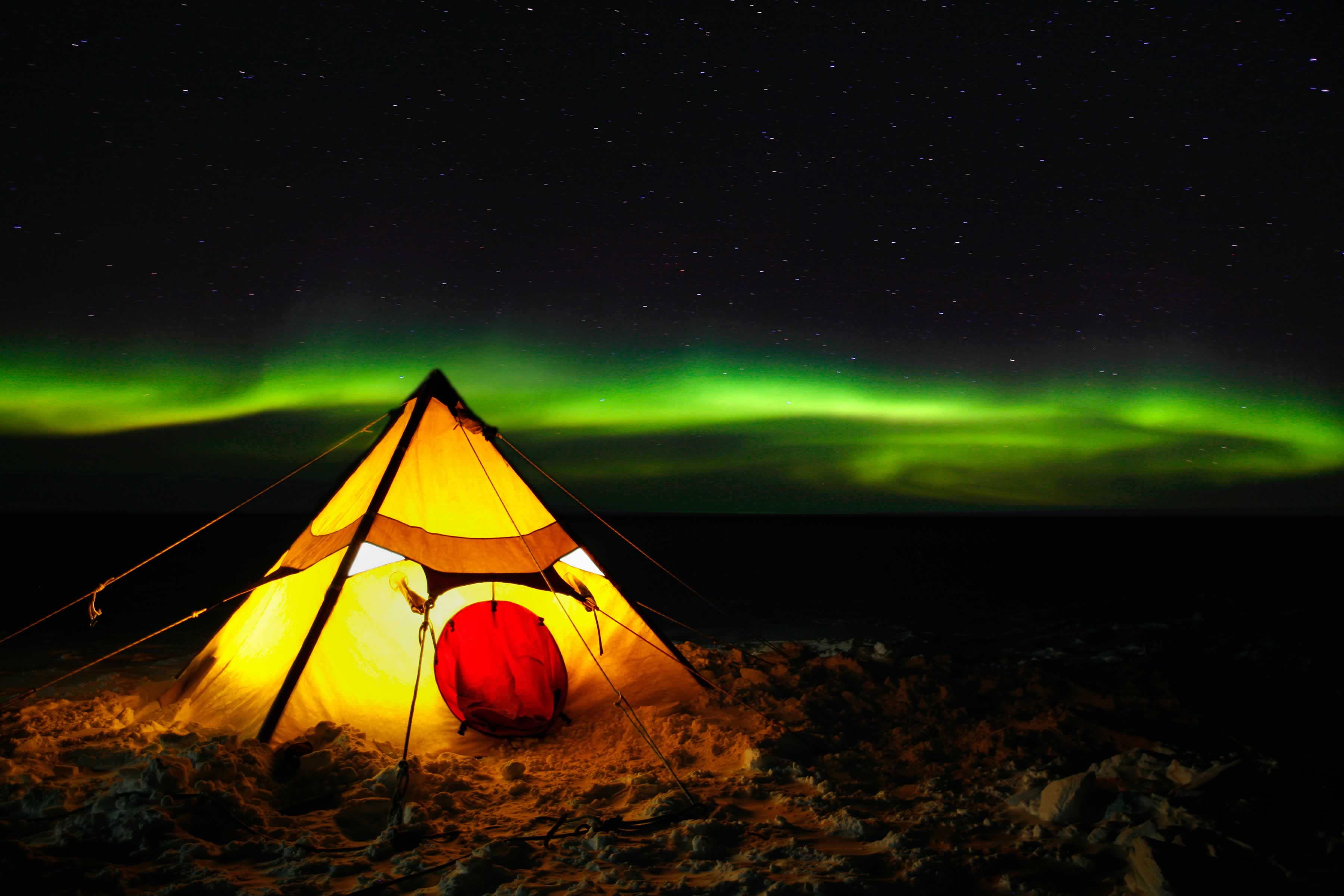 Light from within the tent contrasted against green aurora in the night sky. Photo: Christopher (Chris) Wilson.